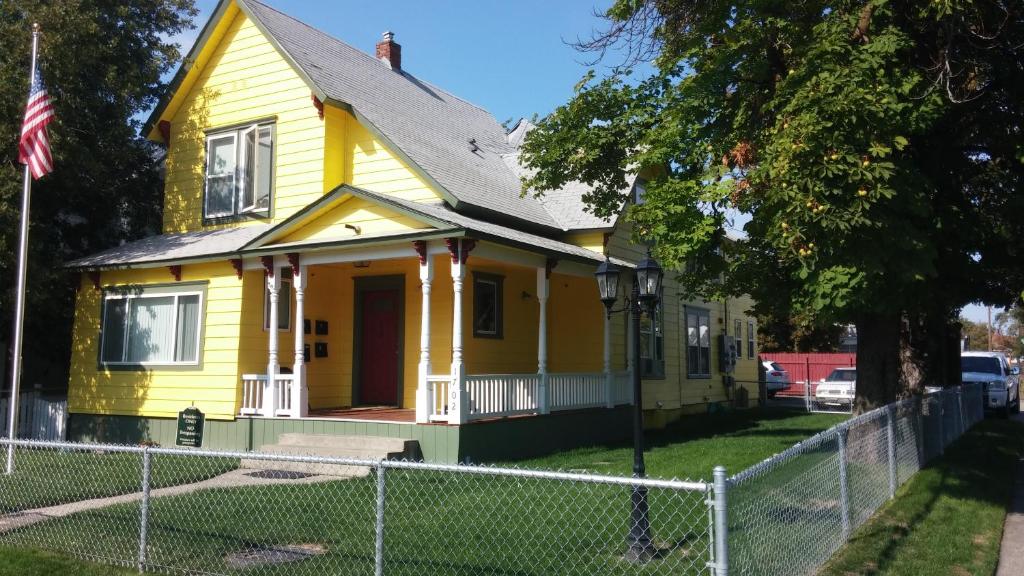 a yellow house with a fence in front of it at Maple Leaf Manor Suites in Spokane