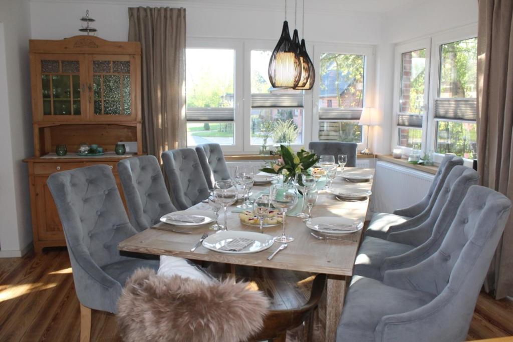 - une salle à manger avec une table, des chaises et des fenêtres dans l'établissement Eulenhaus Osterhever, à Osterhever