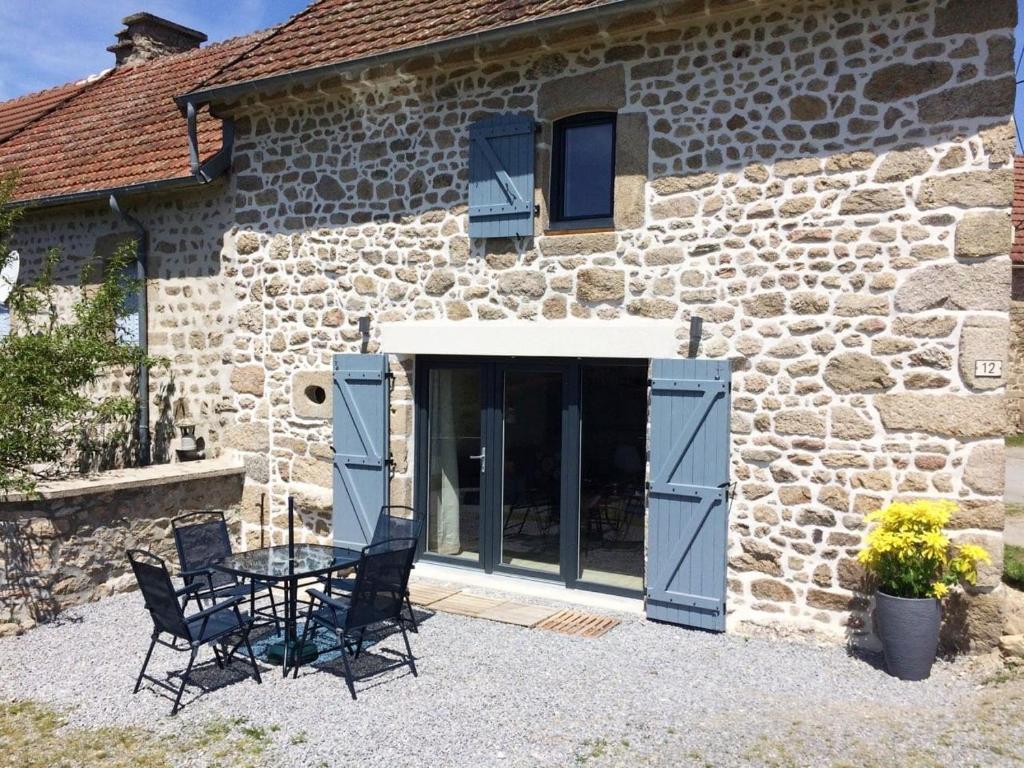 een stenen gebouw met een tafel en stoelen ervoor bij Charmante maison de campagne, 10 min d Aubusson in Saint-Marc-à-Frongier