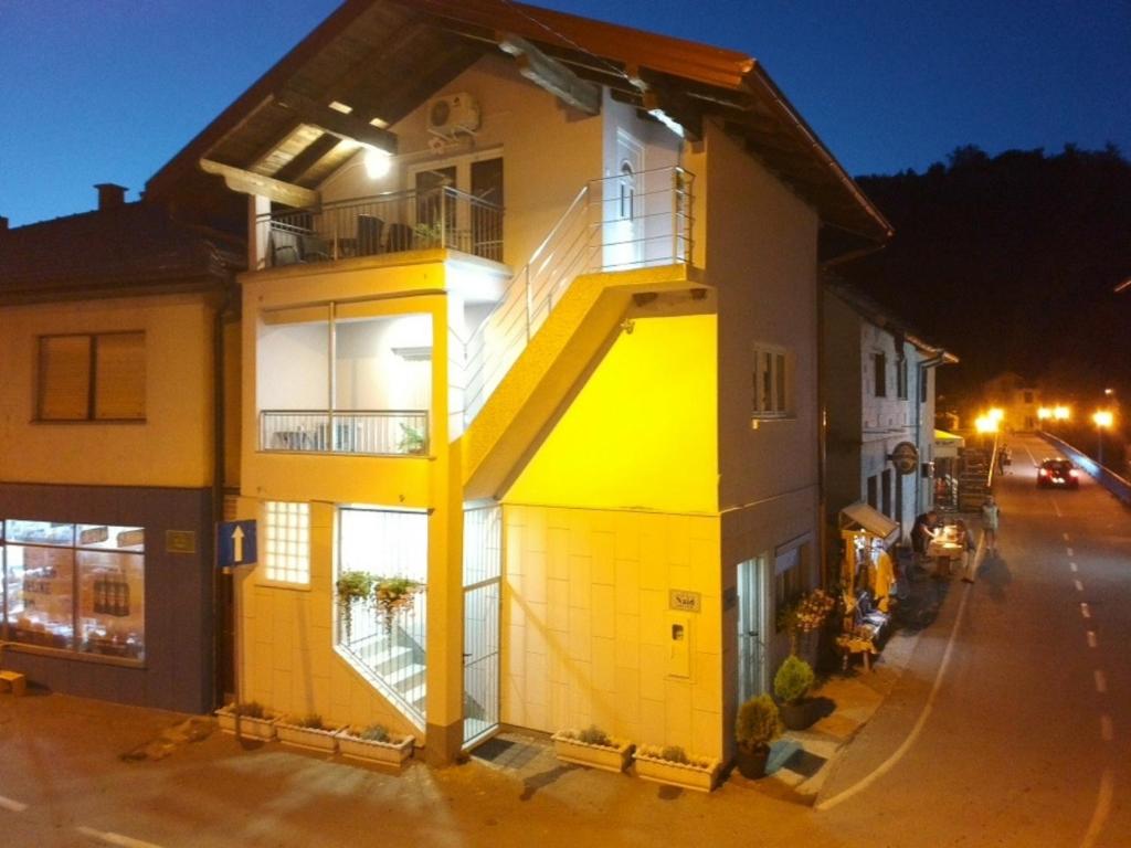 an apartment building with a yellow door at night at Naid Apartmani in Kulen Vakuf