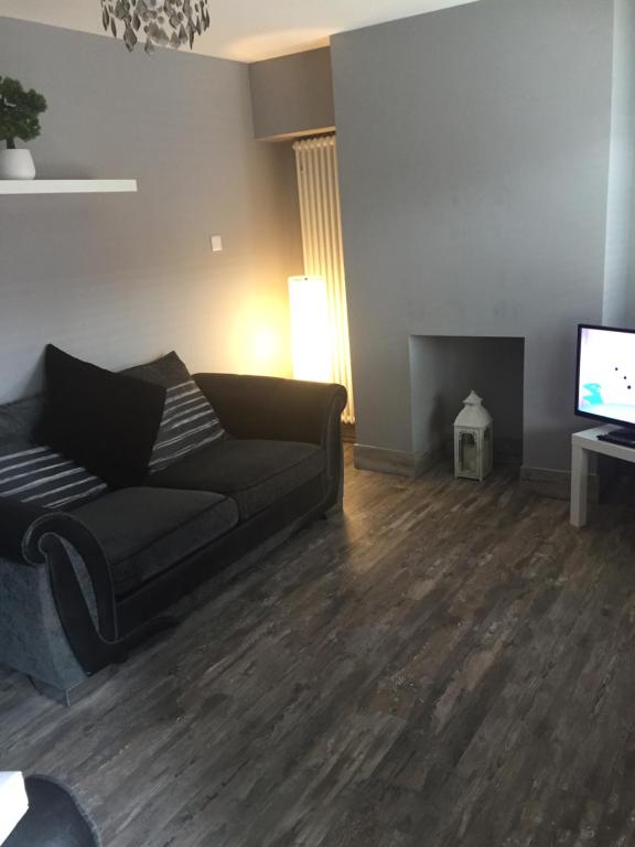 a living room with a black couch and a television at 2 bedroom house Belfast city in Belfast