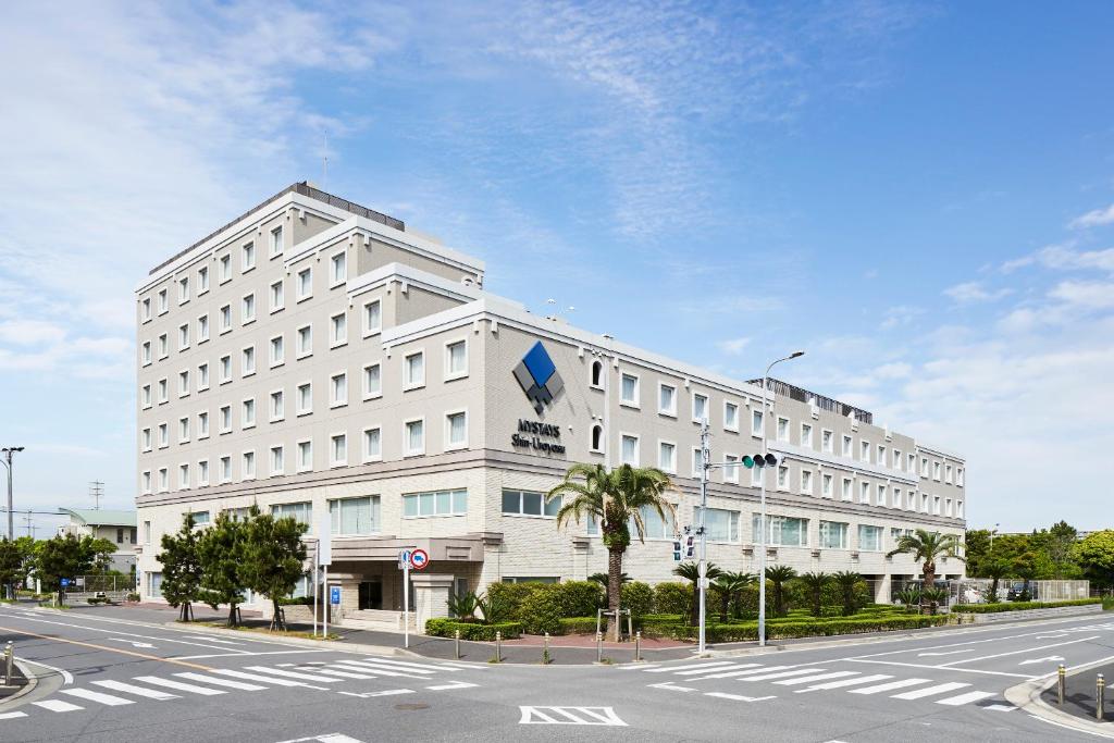 duży biały budynek na ulicy z drogą w obiekcie MYSTAYS Shin Urayasu Conference Center w mieście Urayasu