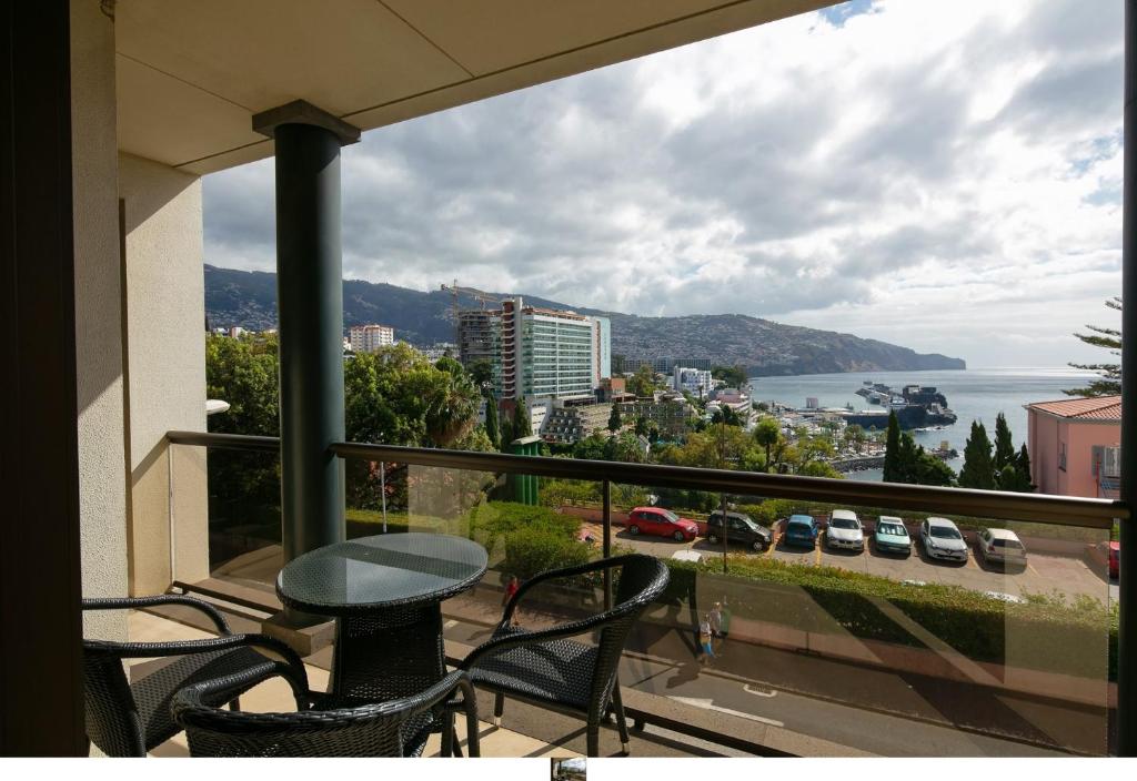a balcony with a table and chairs and a view of the water at Funchal Bay View Holiday Rental in Funchal