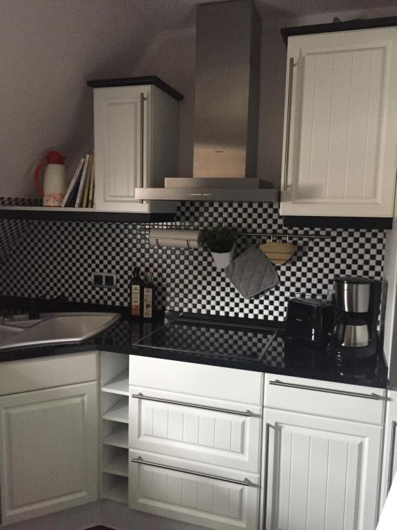 a kitchen with white cabinets and a black counter top at Ferienwohnung „zur Sonne“ in Niederzimmern