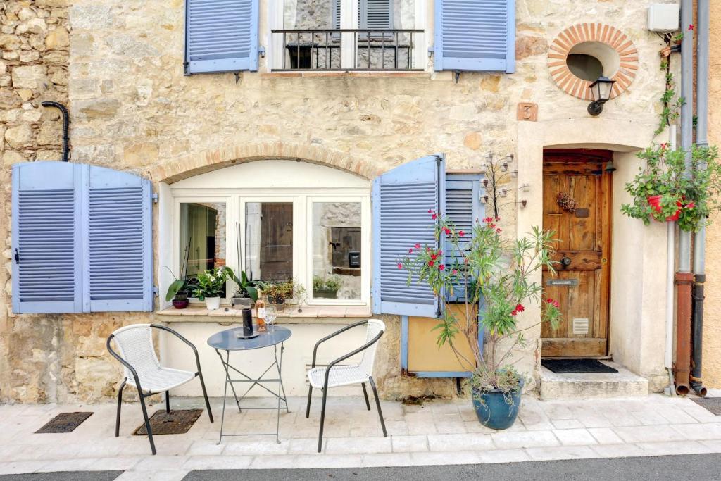 a table and chairs in front of a building with blue shutters at Heart Of Valbonne in Valbonne