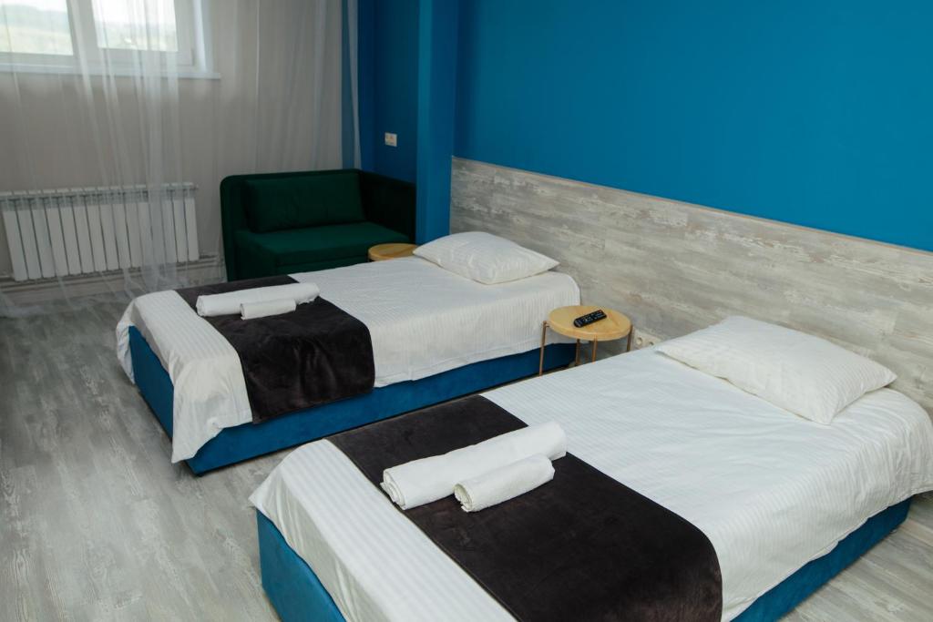 ノヴォクズネツクにある7 rooms Hotelのベッド2台と緑の椅子が備わる客室です。