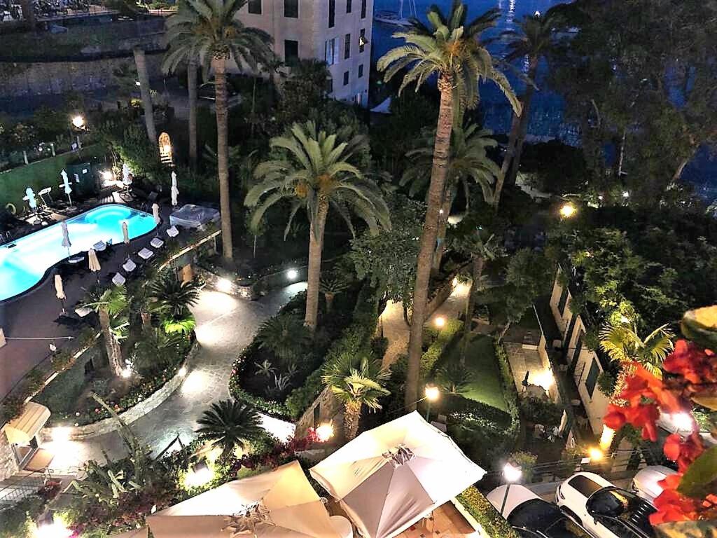 an overhead view of a pool with palm trees and umbrellas at Hotel Metropole in Santa Margherita Ligure