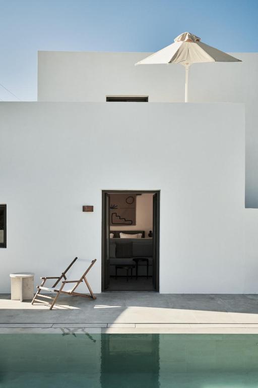 a swimming pool with a chair and an umbrella at Parilio, a Member of Design Hotels in Naousa