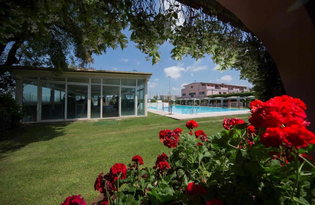 a group of red flowers in front of a building at Mancini Park Hotel in Mostacciano