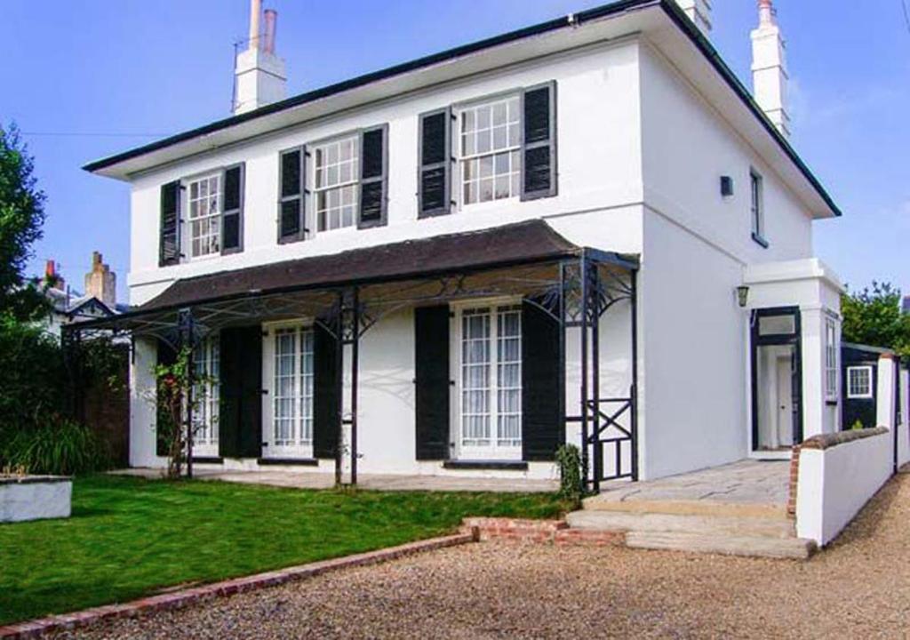 een wit huis met zwarte ramen en een oprit bij Bury Villa - 7 bedrooms sleeping 18 guests in Gosport