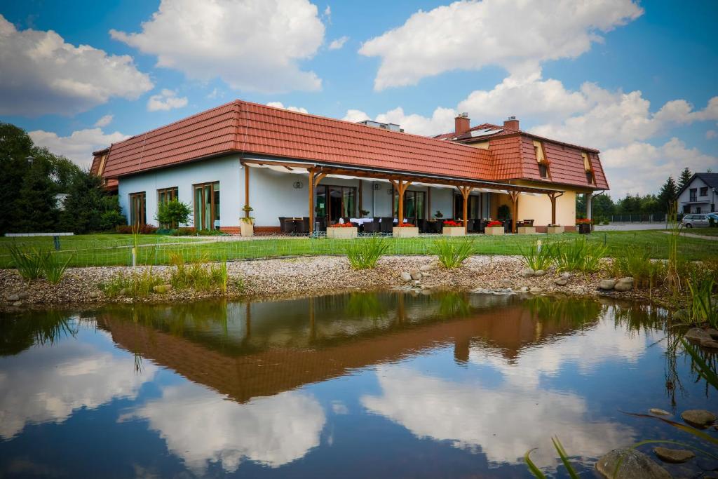 une maison avec un toit rouge et un étang dans l'établissement Zielony Ogród, à Zabrze