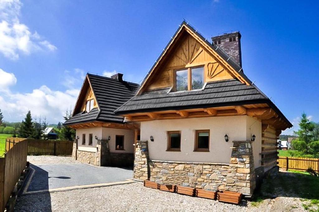 a house with a black roof on a driveway at Domki u Wilka in Poronin