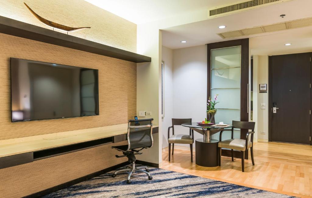 A suite work area with a desk, office chair, television and small dining setting.