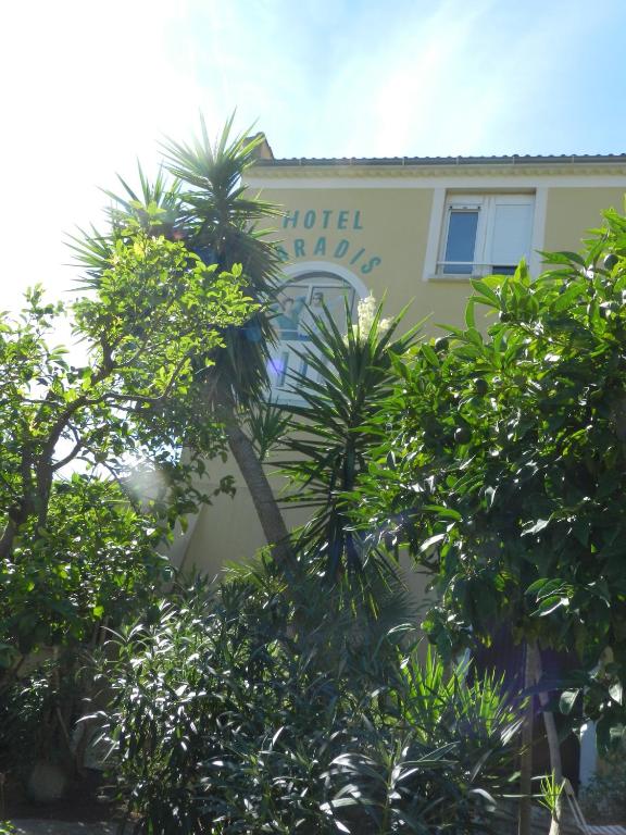 a hotel building with trees in front of it at Hôtel Paradis in Bormes-les-Mimosas