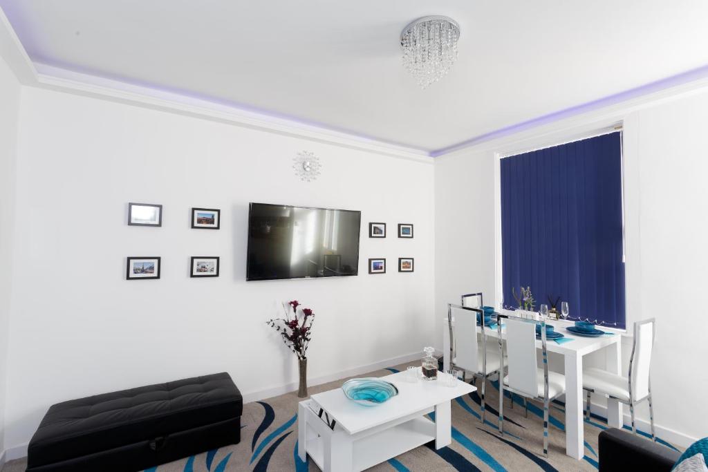 a white living room with a table and a chair at Clifton Bespoke Serviced Apartments in Leeds