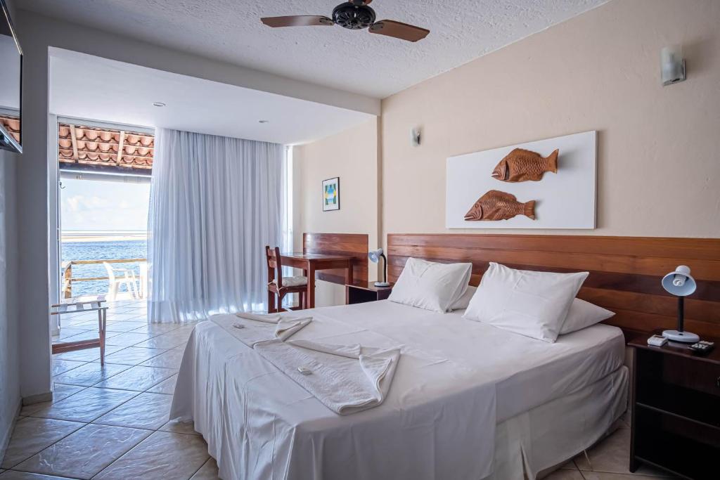 a bedroom with a bed and a table and a window at Pousada Villa do Sol in Genipabu