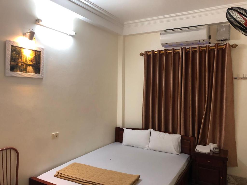 um pequeno quarto com uma cama e uma janela em V A Motel em Hai Phong