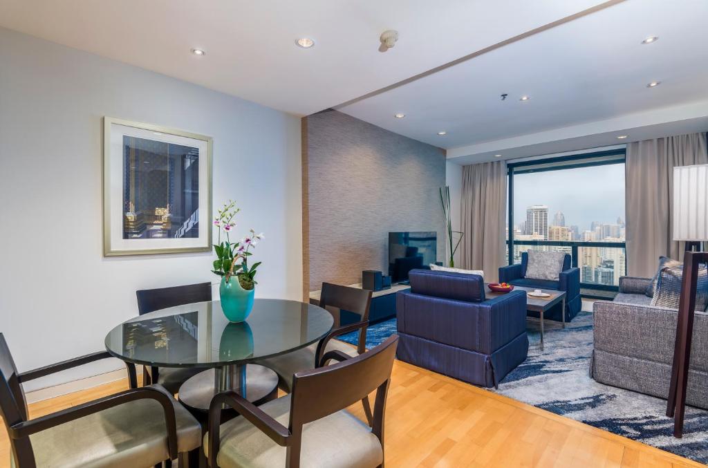 A spacious suite living room with a dining table, sofas and a city-facing window.