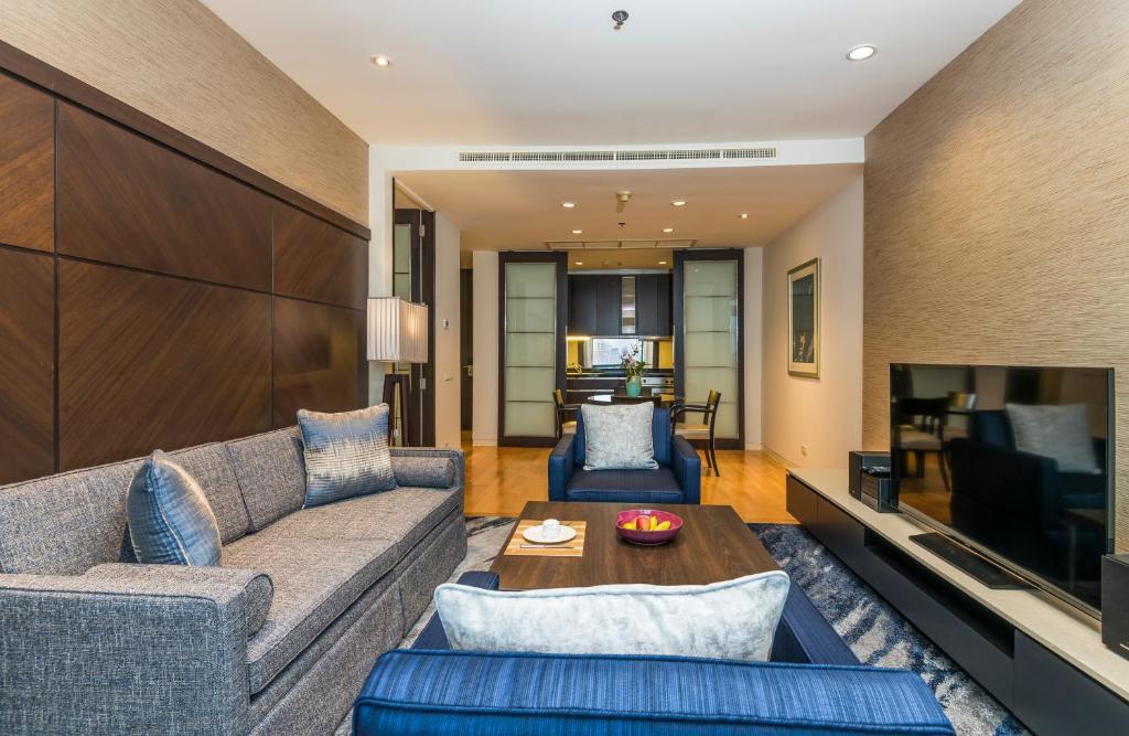 A furnished suite lounge with sofas, a television and a view toward the dining and kitchen area.