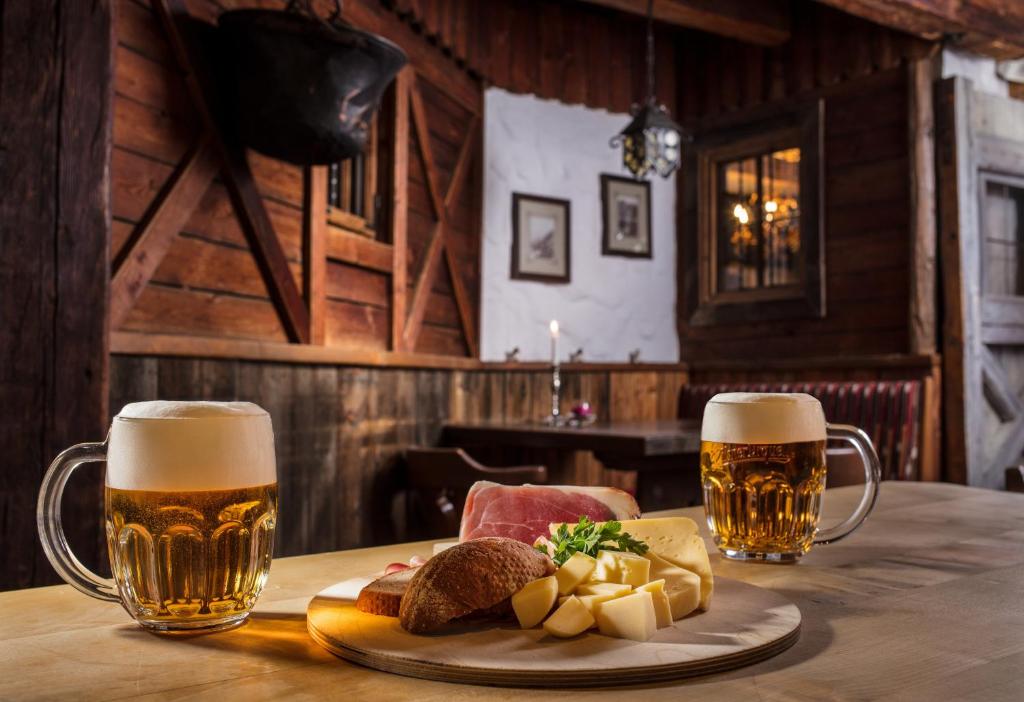 two glasses of beer and a plate of food on a table at Hotel Höhlenstein in Tux