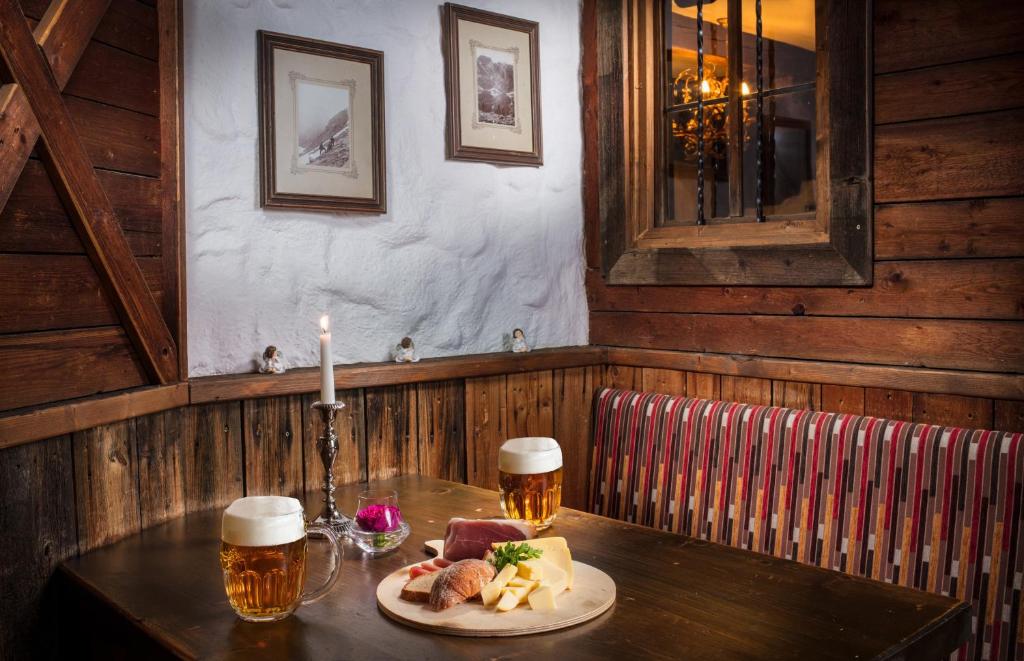 a table with a plate of food and two glasses of beer at Hotel Höhlenstein in Tux