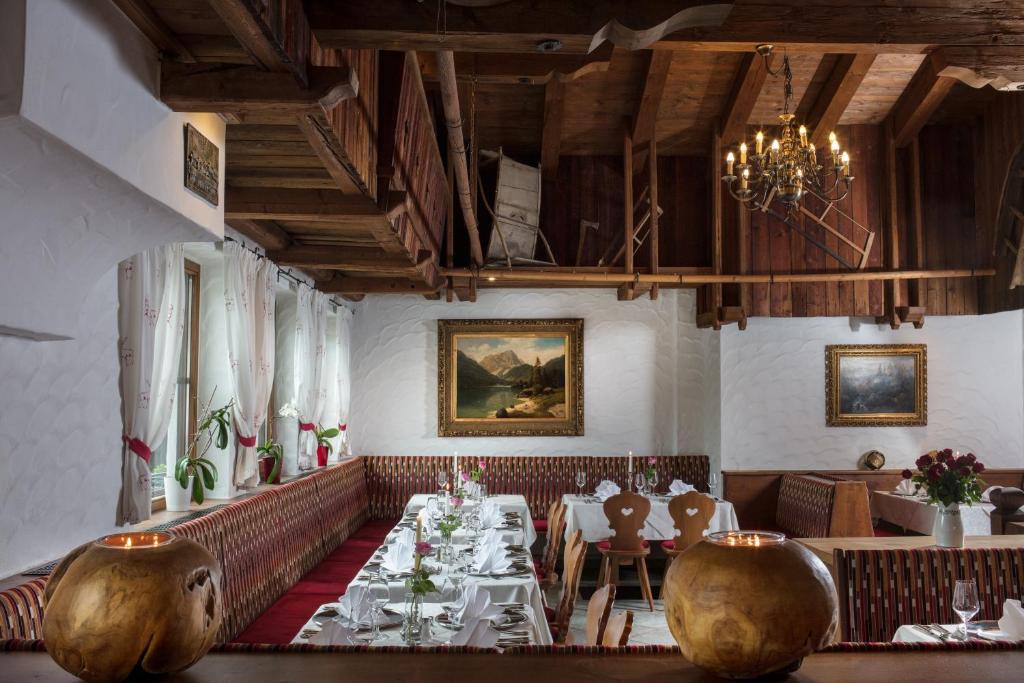 a dining room with tables and chairs and a chandelier at Hotel Höhlenstein in Tux