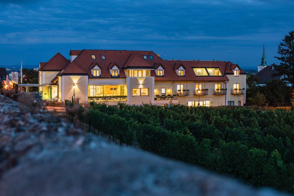 a large house with lights on in the evening at Hotel Turmhof in Gumpoldskirchen