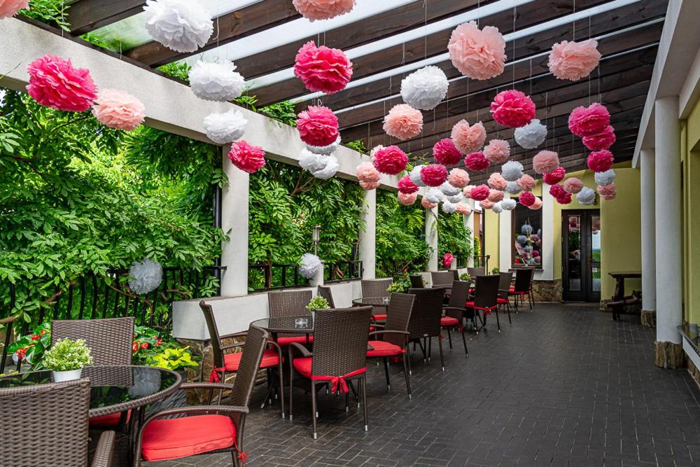 patio ze stołami i krzesłami oraz różowymi i białymi dekoracjami w obiekcie Hotel Konstancja w mieście Konstantynów Łódzki