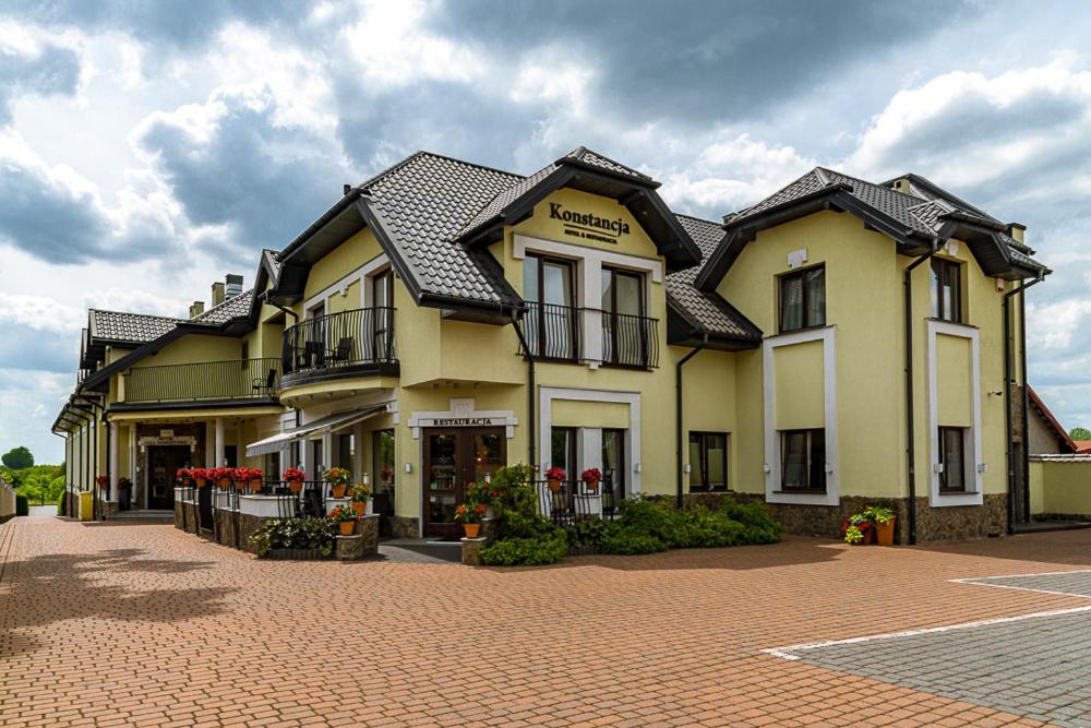 duży żółty budynek przy ceglanej drodze w obiekcie Hotel Konstancja w mieście Konstantynów Łódzki