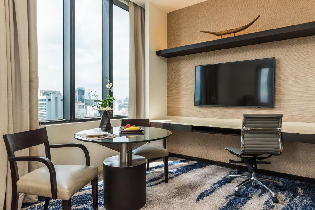 A suite workspace and sitting corner beside tall windows overlooking the city.