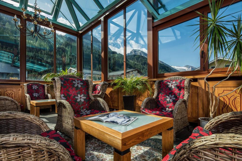 a conservatory with a table and chairs and windows at Hotel Höhlenstein in Tux