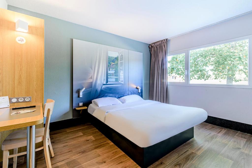 Habitación de hotel con cama, escritorio y mesa. en B&B HOTEL Besançon Chateaufarine, en Besançon