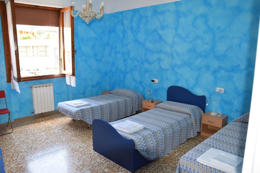 Habitación azul con 2 camas y ventana en camera trebbio, en San Piero a Sieve