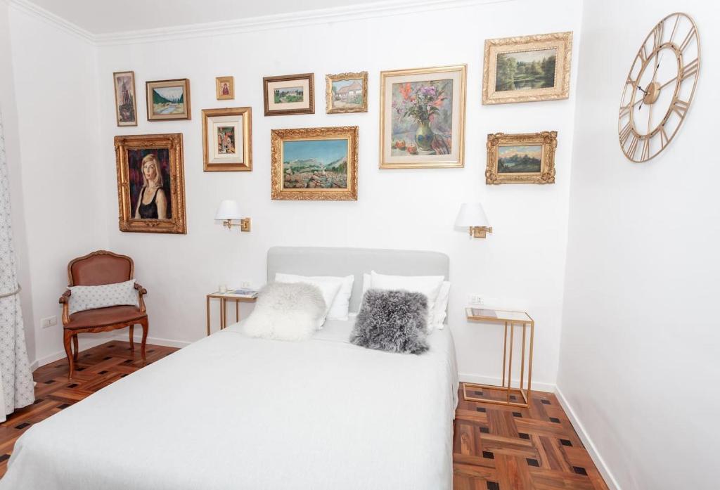 een slaapkamer met een wit bed en ingelijste foto's aan de muur bij Charmant 2 pieces frontiere Monaco in Beausoleil