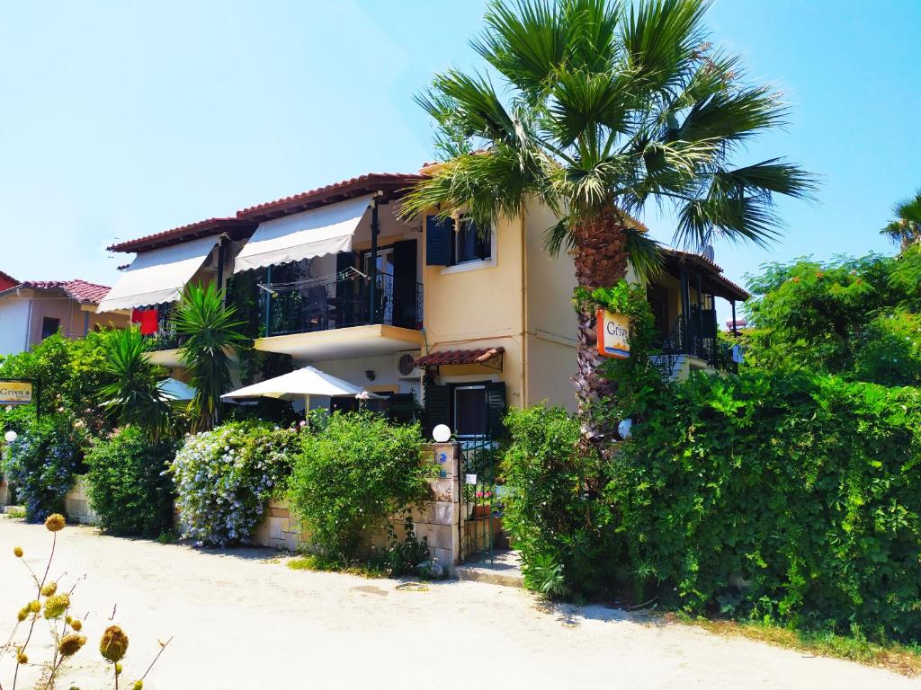 a building with a palm tree in front of it at Grivas Apartments in Syvota