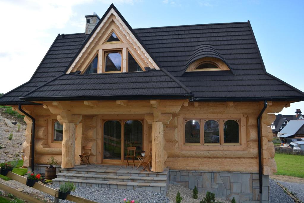 uma cabana de madeira com um telhado preto em Osada Witów - dom "Miłosna Górska" em Witów