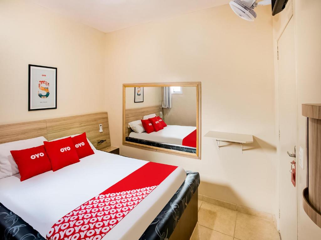 a bedroom with two beds and a mirror at OYO Hotel Itarantim, São Paulo in Sao Paulo