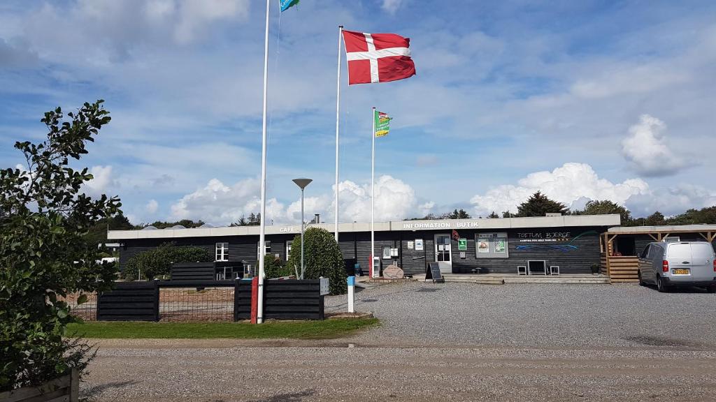 two flags are flying in front of a building at Toftum Bjerge Camping & Cottages in Humlum