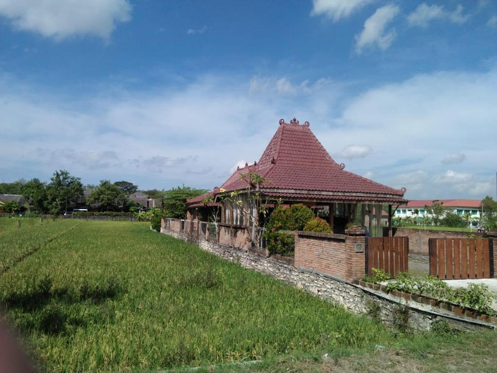 een oud gebouw met een rood dak in een veld bij JOGLOPARI GuestHouse bukan untuk pasangan non pasutri in Bantul