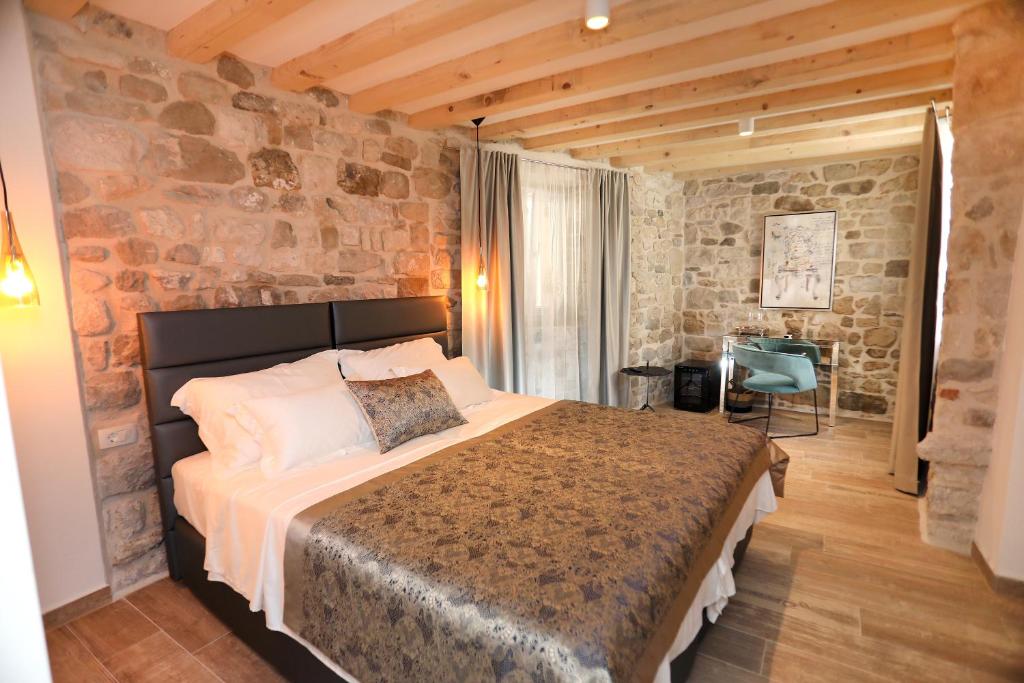 een slaapkamer met een groot bed en een stenen muur bij Villa Teuta in Trogir