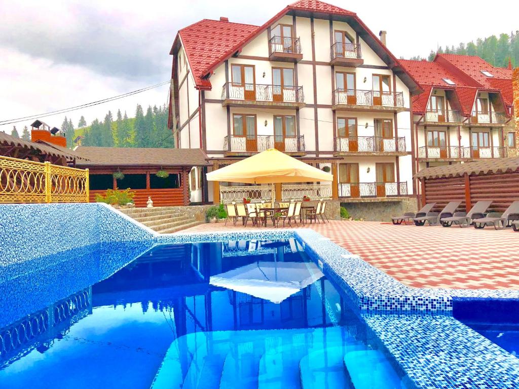 a hotel with a swimming pool in front of a building at Villa Nikoletta in Bukovel