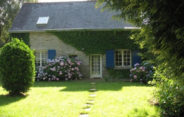 una casa con una puerta azul y flores en el patio en Adorable Penty en pierres en bord de mer, en Tréogat