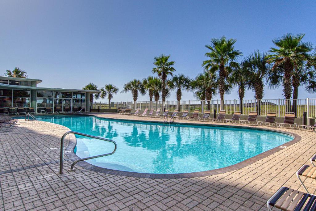 a large swimming pool with palm trees and a building at Tidewater Condos on Orange Beach in Orange Beach