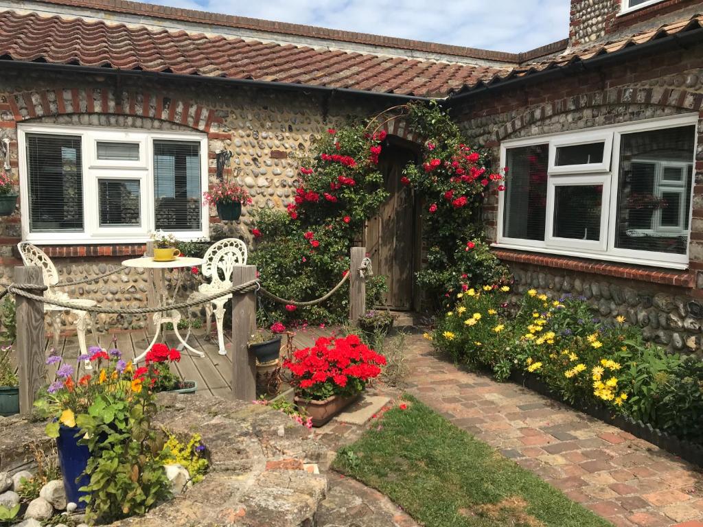 een huis met bloemen en een tafel en stoelen bij Copper's Cottage in Sheringham