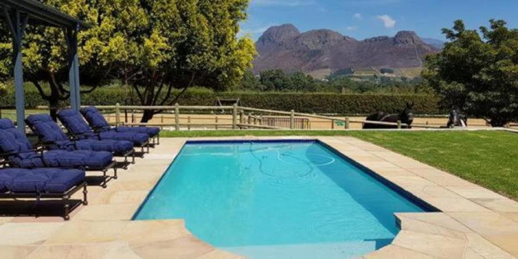 a swimming pool with lounge chairs next to a mountain at Verdun Country House in Franschhoek
