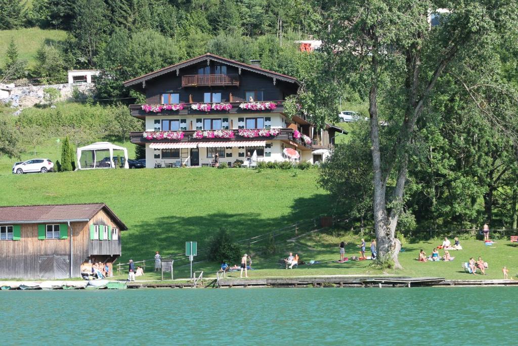 a large house on top of a hill next to a lake at Ticklhof am See in Thiersee