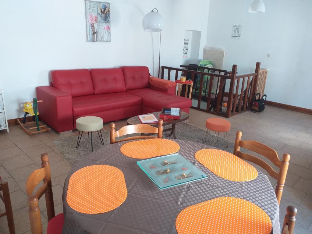 a living room with a red couch and a table and chairs at Joli Appartement de Vacances in Chémery