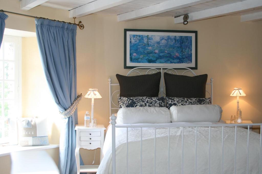 LitteauにあるLa Coulombe Manoir De Hérouvilleのベッドルーム(青いカーテン付きの白いベッド1台付)