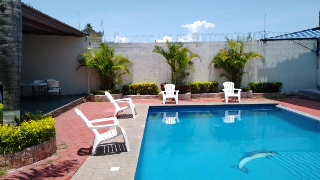 a swimming pool with white chairs and a swimming pool at Family villa in Tequesquitengo