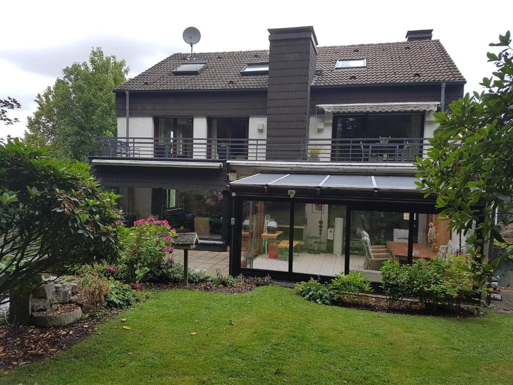 a house with a conservatory with glass doors and a yard at Ferienwohnung mit Pool und Spa in Witten in Witten